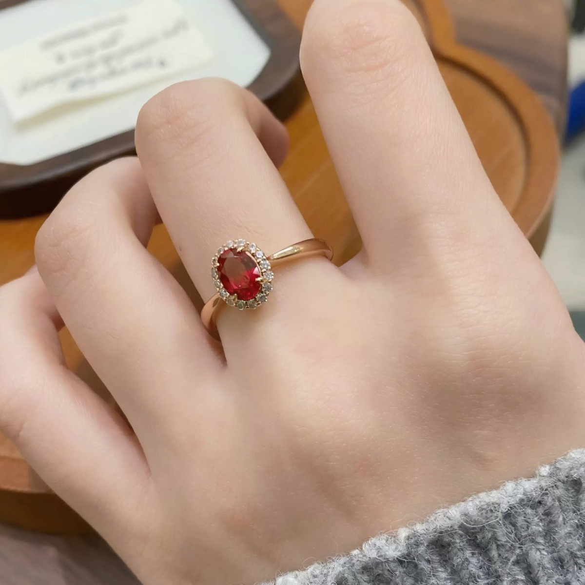 Close-up of oval lab-grown ruby halo ring for proposals