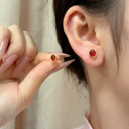 Close-up of oval lab-grown ruby bezel stud earrings in 16K gold for everyday elegance