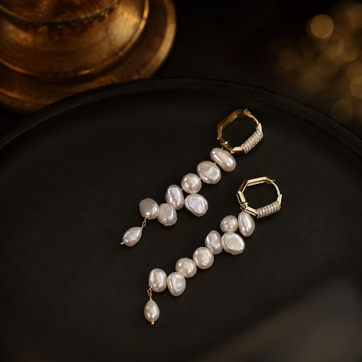 Baroque freshwater pearl drop earrings in 14K gold styled on a dark luxury background