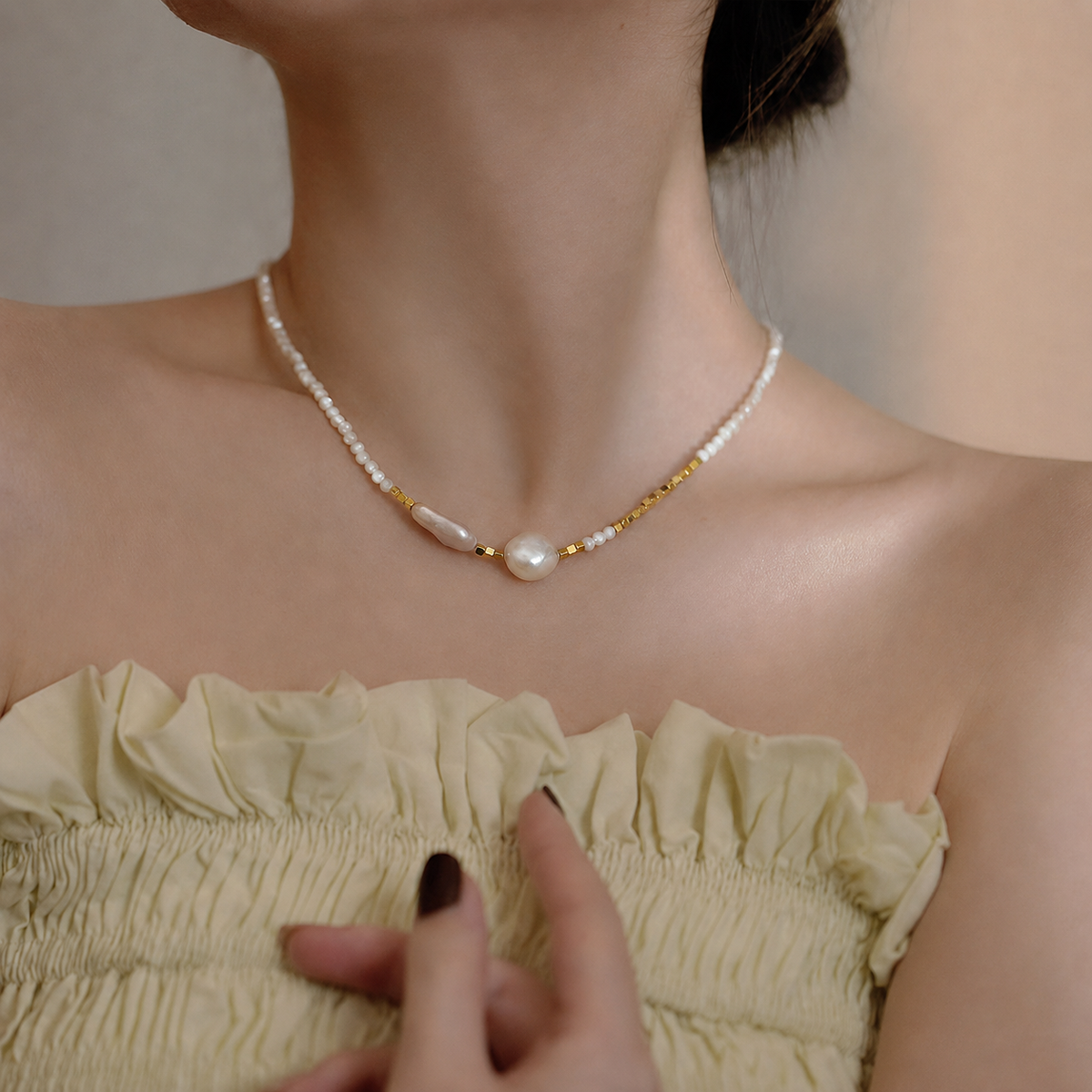 Close-up of a baroque pearl and 14K gold necklace worn at the collarbone