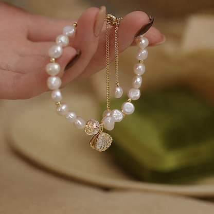 Adjustable gold-tone chain and freshwater pearl bracelet held in the hand