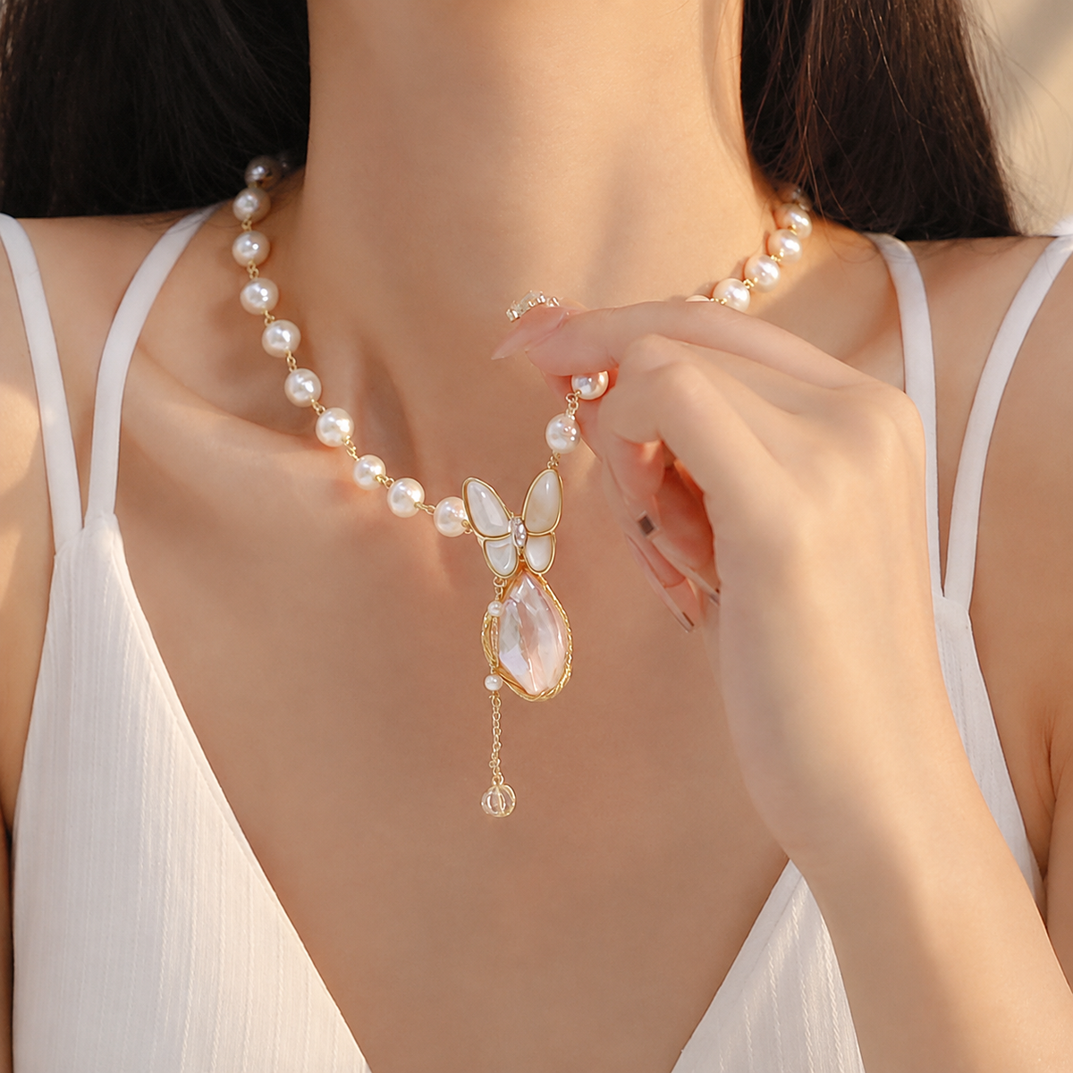Close-up of the Papillon pearl necklace worn with a white dress
