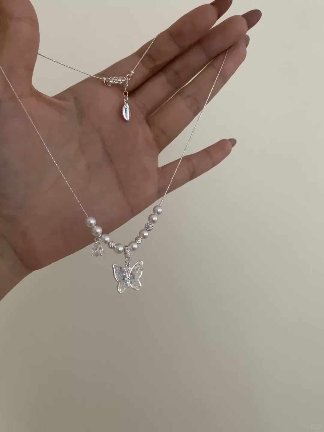 Video view of butterfly pendant high-lustre freshwater pearl necklace styled for weddings