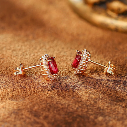 Close-up of oval lab-grown ruby halo stud earrings in 14K gold for anniversary gifts