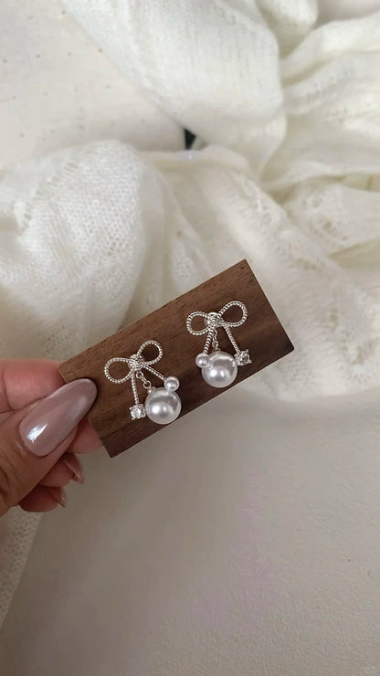 Styled view of bow drop high-lustre freshwater pearl earrings for wedding guest looks