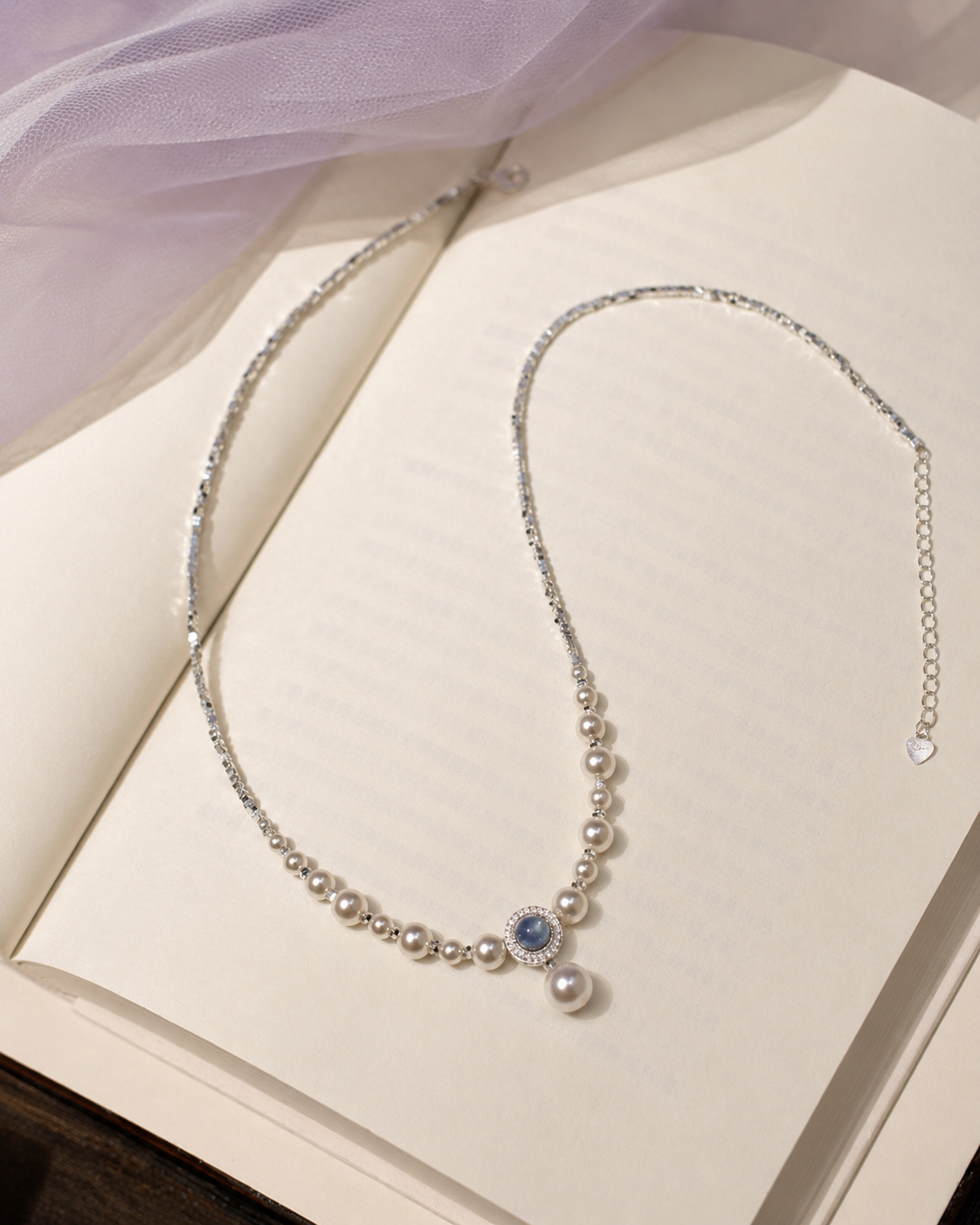 Freshwater pearl and aquamarine pendant necklace styled on an open book