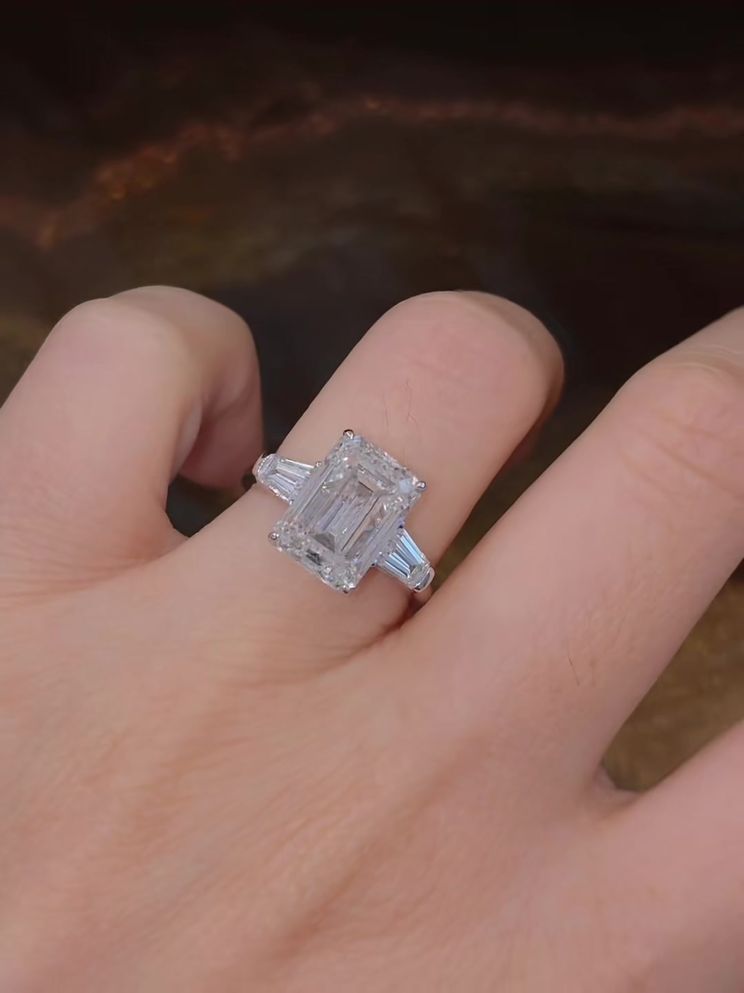 Close-up of lab-grown diamond emerald cut trilogy engagement ring for timeless proposals