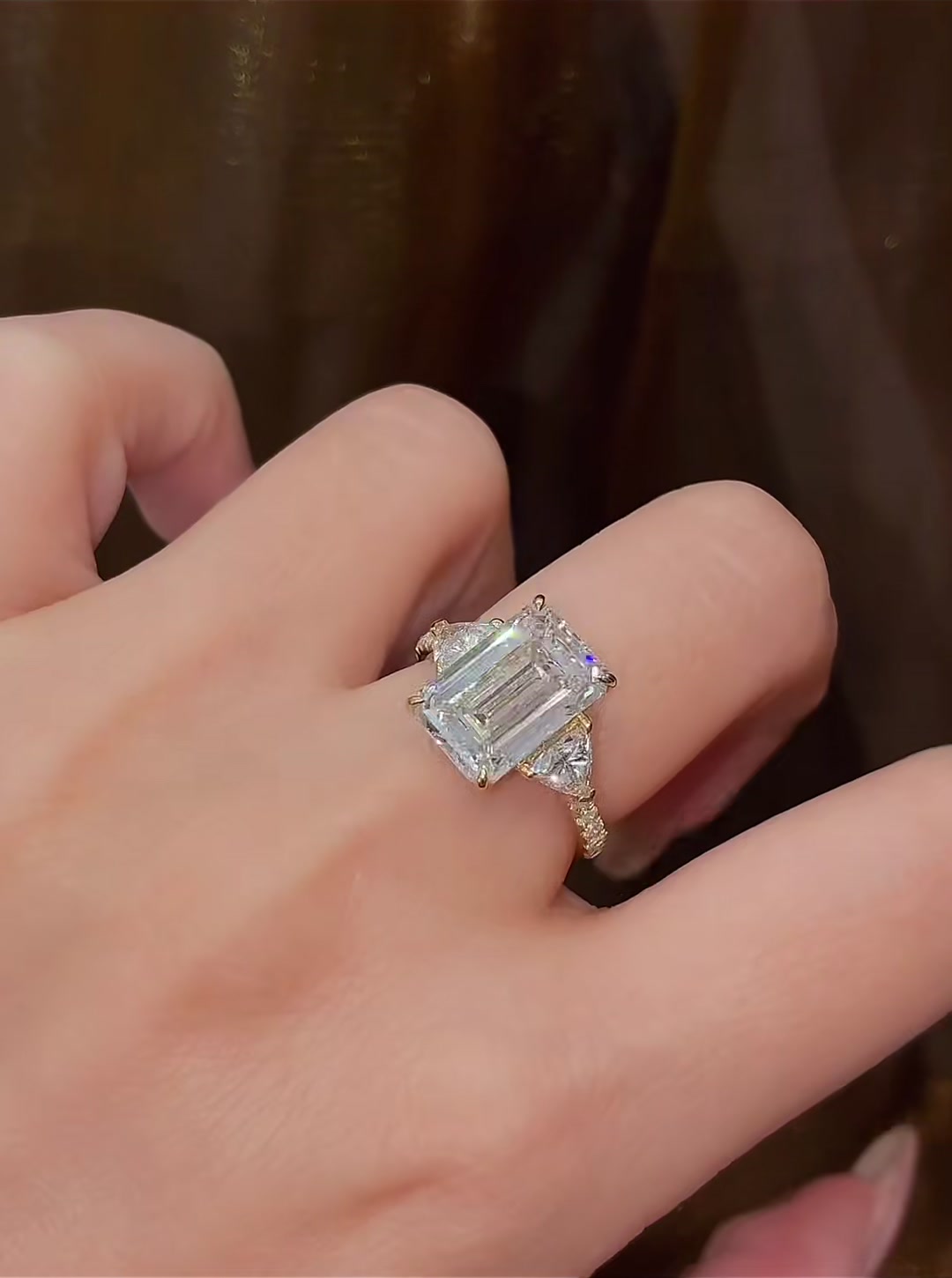 Close-up of lab-grown diamond emerald cut three stone ring for elegant proposals