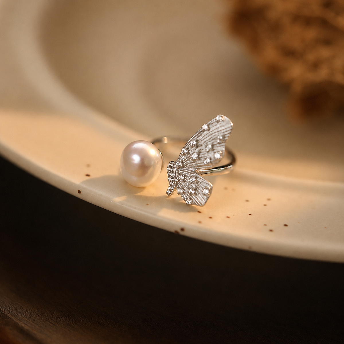 Detailed side view of a pearl and sterling silver butterfly open ring